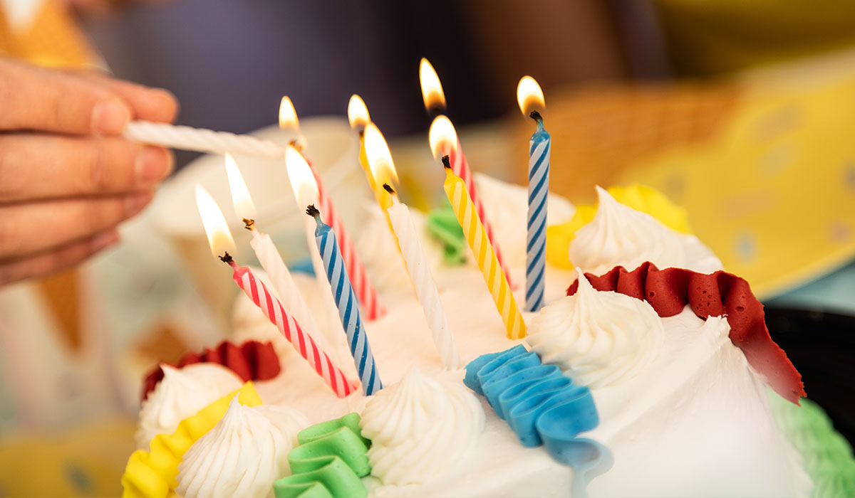 An Over The Top Ice Cream scooper lights the candles on an ice cream cake for a birthday party being celebrated in the party room.