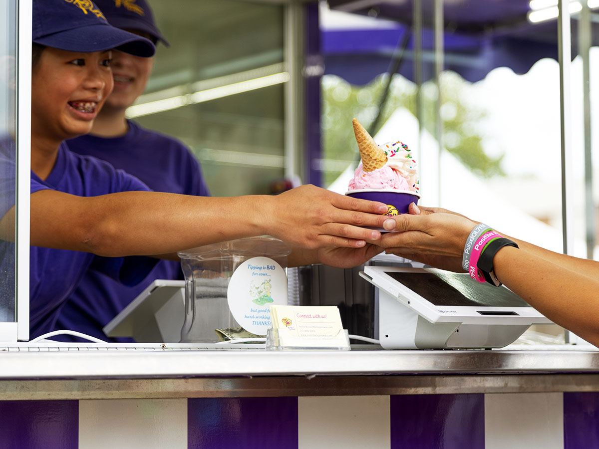 An Over The Top Ice Cream scooper serving a fairgoer a sundae at the Iowa State Fair.
